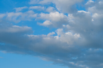 Naklejka na ściany i meble Bright blue sky with white fluffy clouds and bright sunlight.