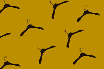 Pattern from plastic fashionable hangers under a tree on a yellow background with a hard shadow. Concept store, sale, design, empty hanger. Fashionable lightweight hangers made of durable material.