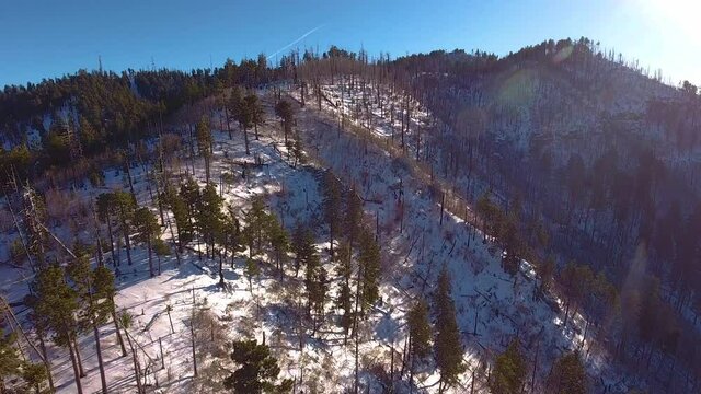 Cinematic rotating drone shot of snow covered Mount Lemmon Arizona starting into the sun