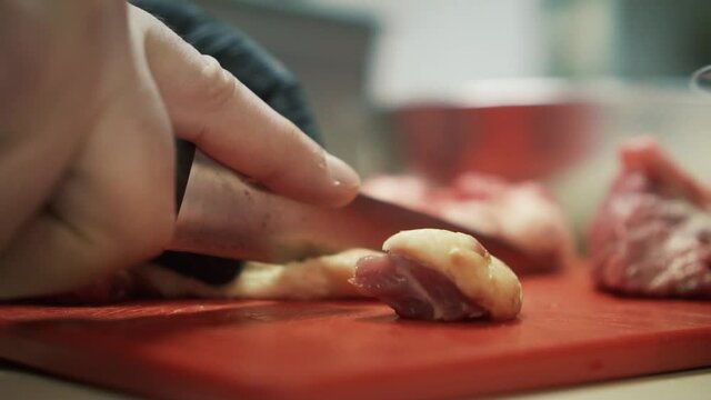 Close up of hand slicing meat with knife. Slow-motion
