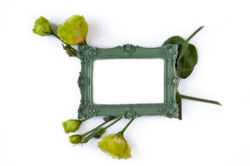 Vintage frame with green flowers flat lay on white.