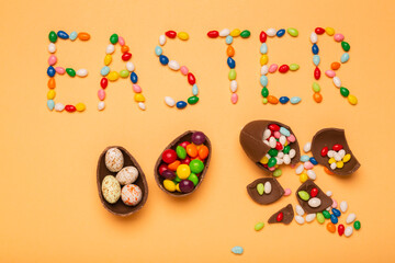 Fototapeta na wymiar Colorful eggs with the word Easter wrote with sweet candies, free space for greeting text. Chocolate eggs as a symbol of Easter