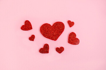 Love theme background with red glitter handmade hearts on pink background. Romantic concept