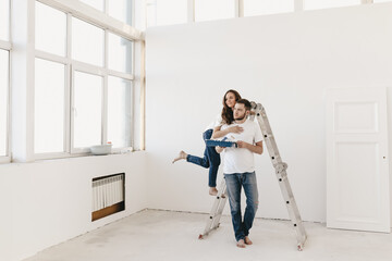 Happy lovers newlyweds a man and a woman are repair in renovation update improvement of the room...