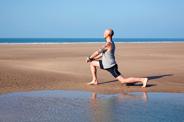 Man (40-44 years old) stretching legs on deserted beach in Woolacombe, North Devon