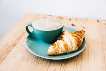 Cappuccino and croissant on wooden table. Morning breakfast concept