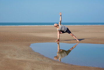Man (40-44 years old) stretching on deserted beach in Woolacombe, North Devon