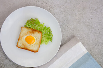 Scrambled eggs in toast on a light gray plate on a gray stone background.