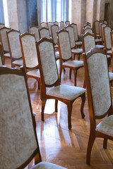 Fototapeta na wymiar Rows of old, vintage chairs. Auditorium room. Rays of sunlight through the window. Training, meeting and business concept. selective focus. Vertical photo