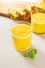 Mango with pineapple smoothie in jug and glasses. Fresh morning breakfast on the table for slimming with yellow fruit