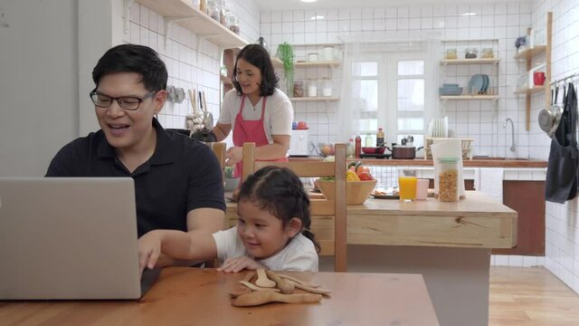 4K Happy Asian family eat breakfast together in kitchen. Asian couple with cute baby daughter preparing food for breakfast meal. Mom and dad with child girl kid enjoy and having fun cooking together.