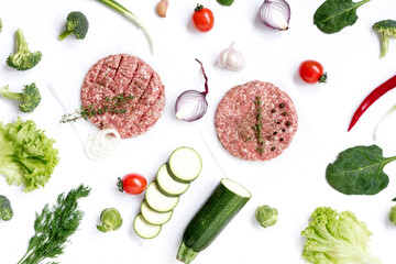 Beef cutlets for homemade burgers  with vegetables. Top view on grocery background