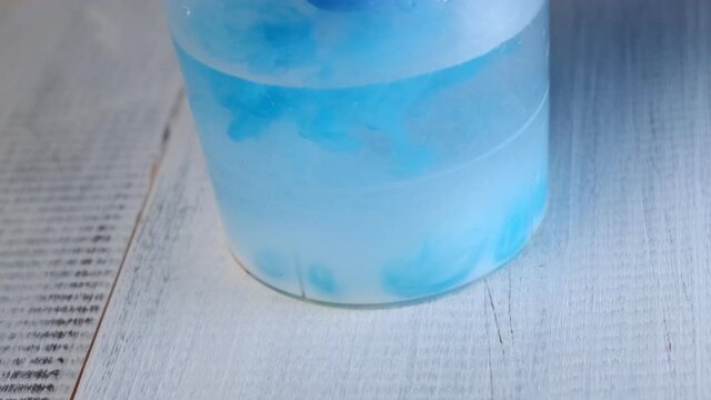 in a clear glass of cloudy water, the blue paint is washed off the brush