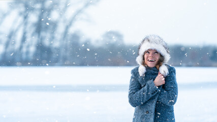 Young attractive woman happy with the falling snow in winter nature