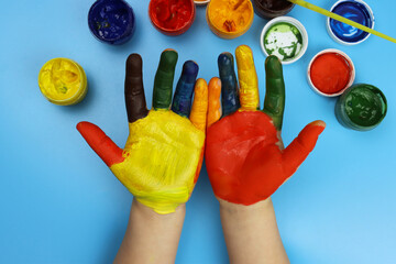 Children's hands painted with colorful bright colors on a blue background