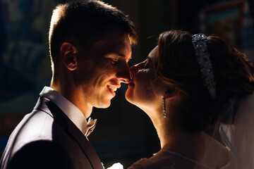 the bride gently kisses the groom. Daylight falls on a dreamy wedding couple standing in a church.