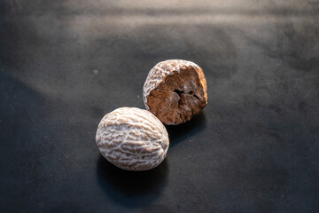 Dried brown nutmeg on shiny black background