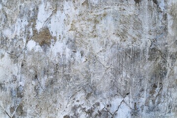 Background texture of an old gray plastered wall with cracks. Traces of old white paint.