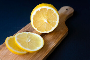 Not a dark background, ripe sliced lemon, tea and honey on a cutting board.