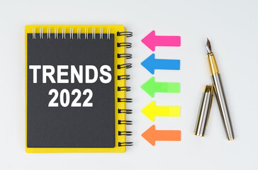 On a white background lies a pen, arrows and a notebook with the inscription - TRENDS 2022