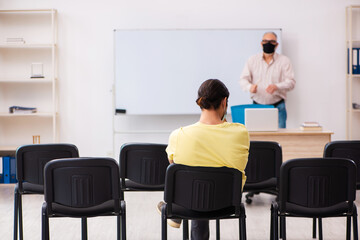 Obraz premium Young male student and experienced teacher in pandemic concept