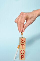 Stop smoking concept, hand extinguishing a cigarette and STOP text on wooden blocks. World No Tobacco Day on May 31 concept. Selective focus