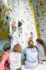 Hübsche, nette, freudliche Jungen und Mädchen beim Klettern, Bouldern. Die Kinder, 8 bis 12 Jahre alt, freuen sich Hallensport zu treiben und auszutoben. Fitness, Gesundheit, Spass für die Familie.