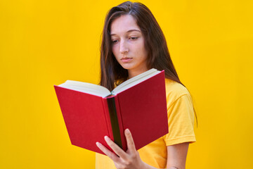 Caucasian young girl with reading a red book on yellow background