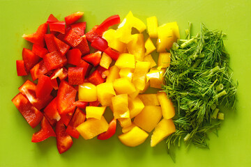 healthy sliced raw vegetables, red and yellow peppers and green parsley on a cutting board
