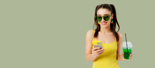 Beautiful happy young woman wearing summer outfit and sunglasses holding mobile phone