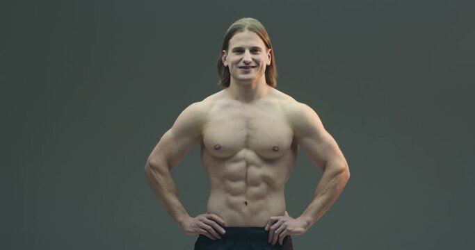 Handsome healthy athletic guy fitness model on gray studio background. Video of muscular fashion male with naked torso
