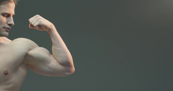 Muscular naked arm. Athletic guy showing biceps and triceps muscles on gray studio background. Close up video