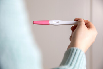 Young woman holding negative pregnancy test,home pregnancy test showing negative result close up