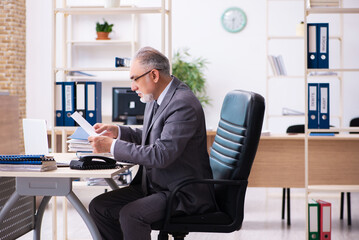 Old male employee and paperwork in the office