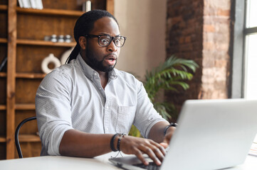 Upset business man working with laptop computer in office, feeling stressed and anxious for...