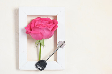 rose flower and key in frame on beige background