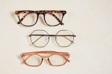 several fashionable stylish glasses on a beige background place copy top view, optics store