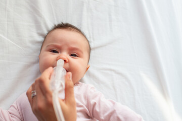 mother using baby nasal aspirator mucus nose suction