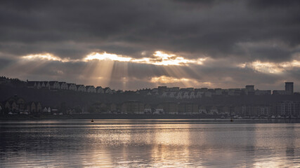 Naklejka na ściany i meble Sun beams bursting through the clouds, over Penarth Marina, on the edge of Cardiff Bay, Wales