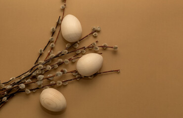 Willow branches and wooden unpainted eggs on a brown background. Easter.