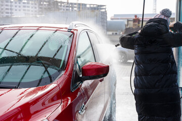 washing car at autowash . Car wash. red machine under the pressure of water at a car wash. car in foam. woman washing car