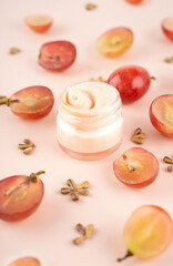 Concept organic extract nature grape seeds oil in cream for skin care in home. Creative modern flat lay composition with fresh red grapes and seeds in pink background. Naturecore. Eco. Close up.