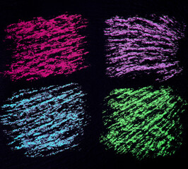 Four multi-colored squares are drawn in chalk on a rough black background. An interesting concept for text or drawing. Red lilac blue and green square. Rough black slate background. Space for text
