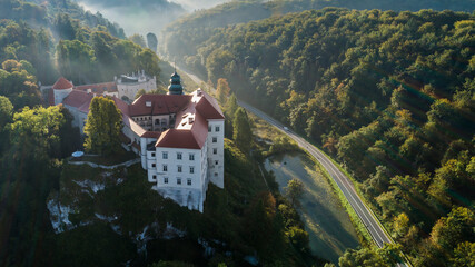 Limestone cliff Pieskowa Skala near Krakow, Poland, with isolated rock "Maczuga Herkuklesa" Hercules's mace
(Hercules cudgel or bludgeon) and historic Renaissance castle in morning fog in fall. Aerial