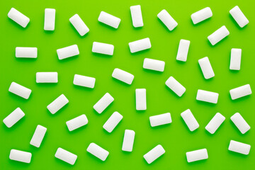 Fototapeta na wymiar Pads of white chewing gum on green background. Fresh mint bubble gum.