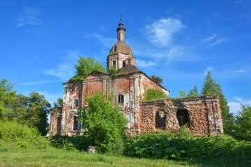 Fototapeta na wymiar an abandoned dilapidated church, overgrown with grass against the background of the sky, surrounded by greenery