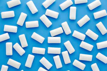 Fototapeta na wymiar Pads of white chewing gum on blue background. Fresh mint bubble gum.