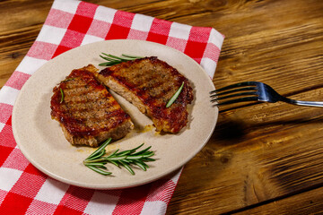 Grilled pork steaks with rosemary on wooden table