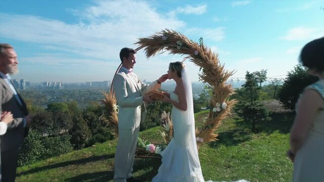 Aerial shot. Groom feeds bride with wedding bread. Slow motion