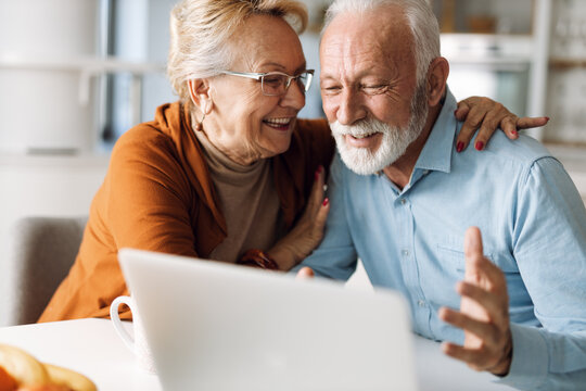 Happy mature couple using laptop at home